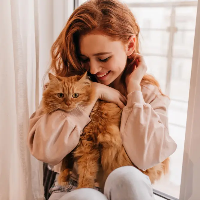 Ginger haired woman cuddling a ginger cat
